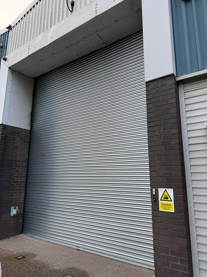 Industrial silver roller shutter door with warning sign